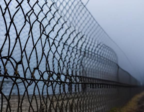 Gloomy Prison Scene with Barbed Wire and Fog