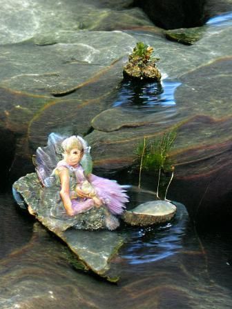 Whimsical Fairy Resting on Waterside Rock
