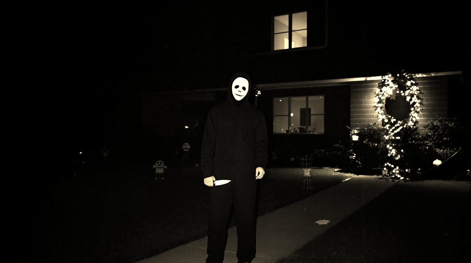 Lone Figure with Knife Under Halloween Lights