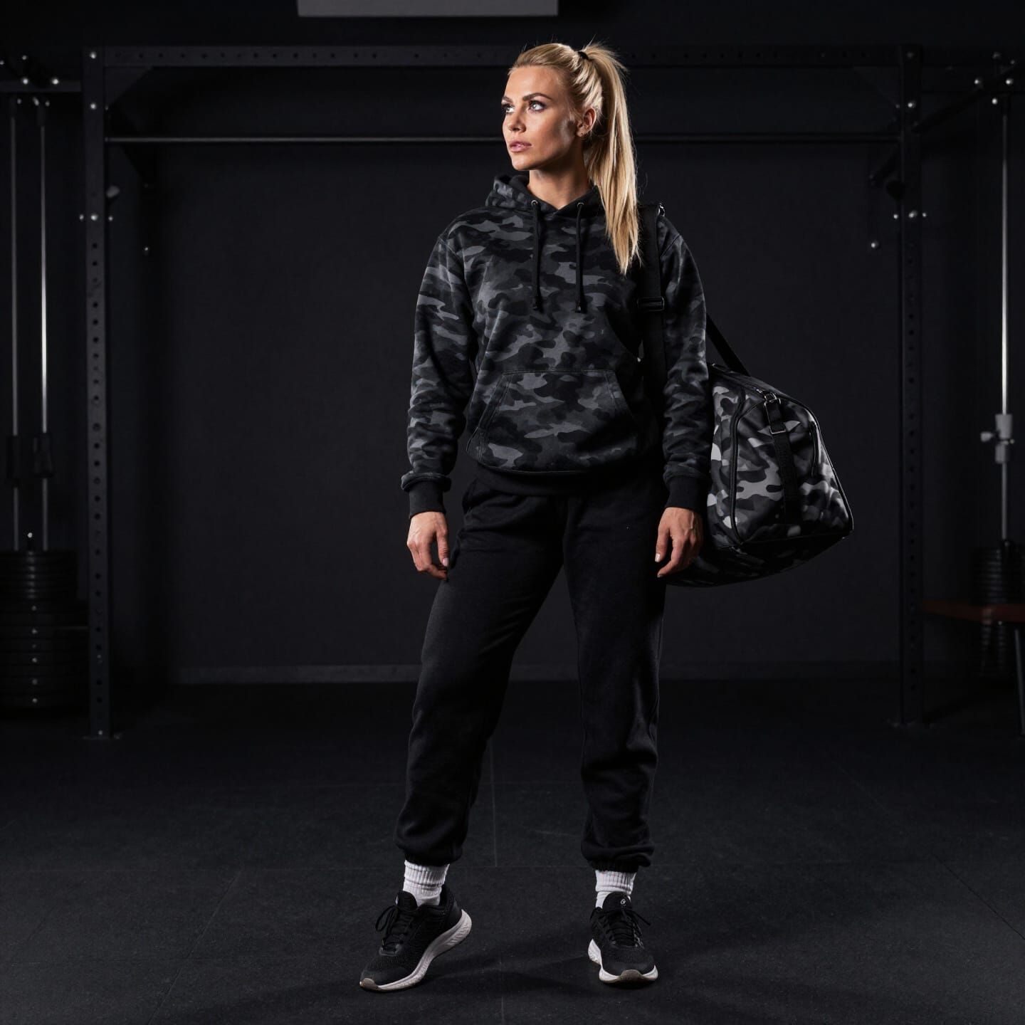 Athletic Woman Prepares for Workout in Dimly Lit Gym