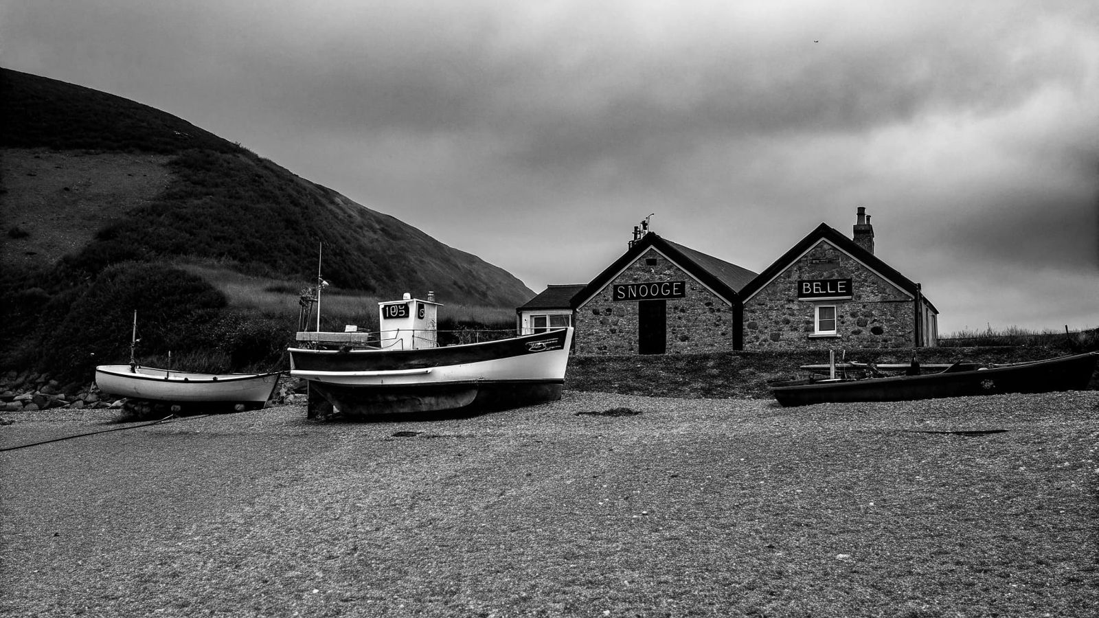 Coastal Stone House with Boats on Shore
