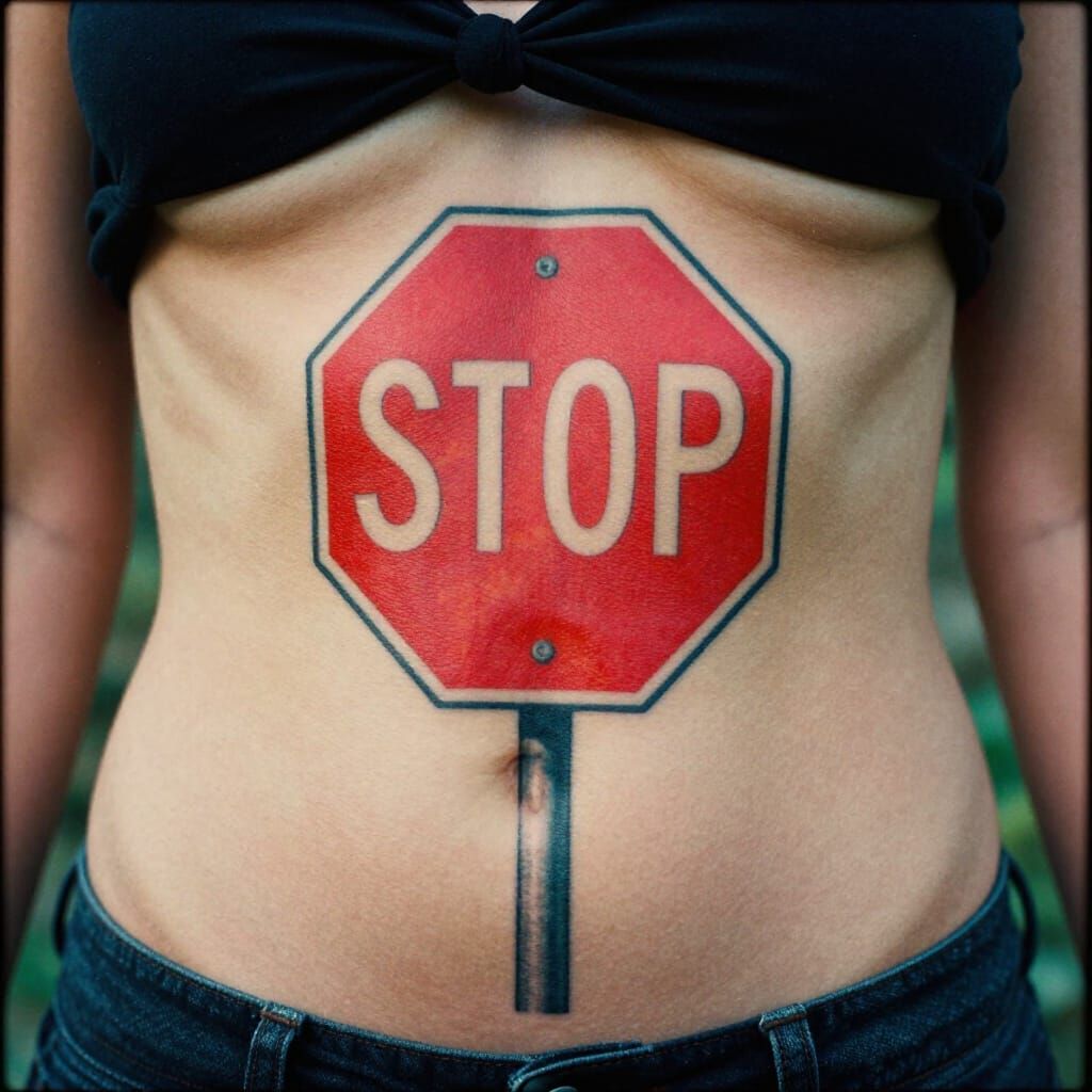 Vibrant Stop Sign Tattoo on Woman's Abdomen