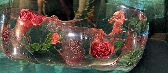 A glass vase with roses. Mermaids are swimming in the water ...