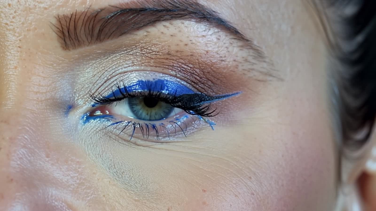 A womans eye, closed, blue eyeshadow, black lashes that wave back and forth as her eye moves around, only her eyelid, ey...