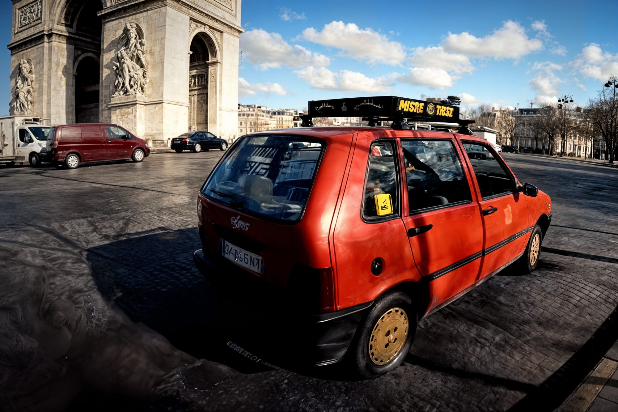 A small, old red city taxi with a slightly weathered exterior, compact and boxy design, white roof sign glowing “TAXI,” driving through busy...