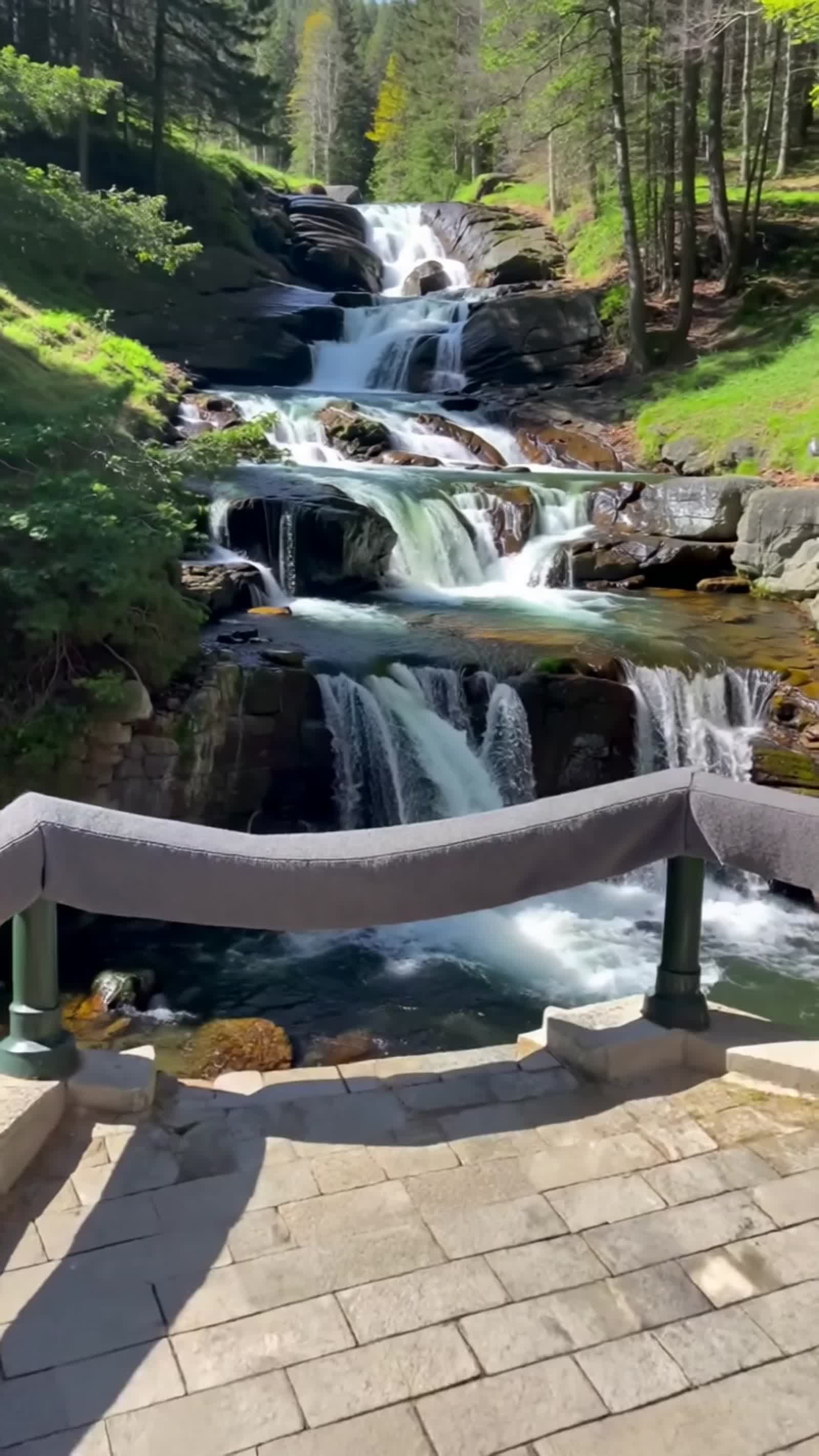 create a photo realistic view of the waterfalls at Bettws y Coed in North Wales United Kingdom, sunny summer day, crysta...