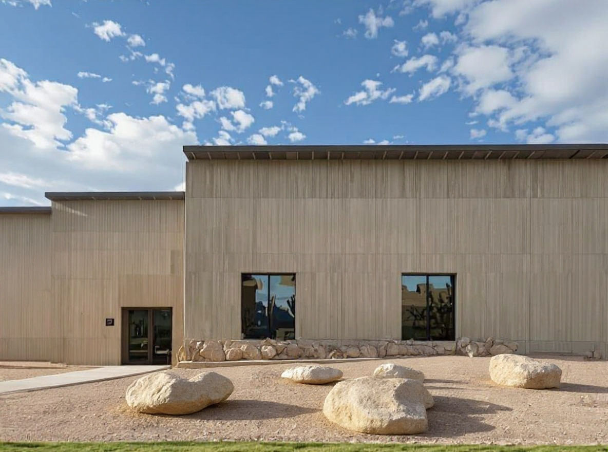 Maintain the existing building exactly as it is. Remove all the planting landscape. Replace with desert style landscape to include large roc...