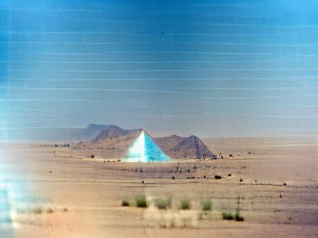 light blue pyramid in the middle of a desert photographed on...