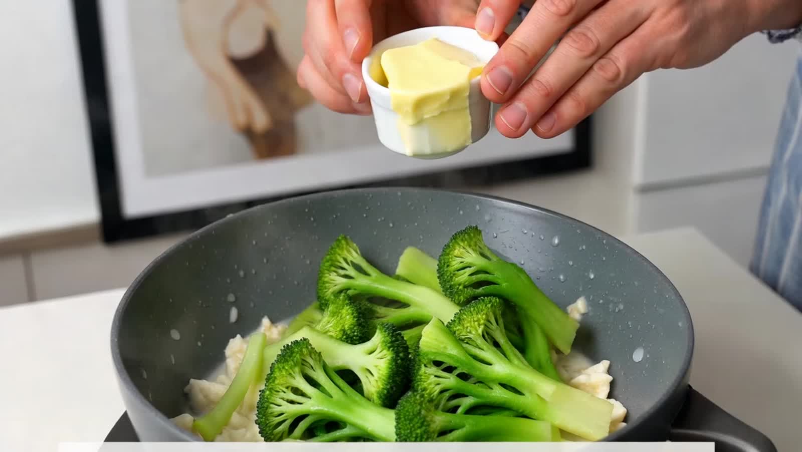 Melting butter over a steaming bowl of broccoli.