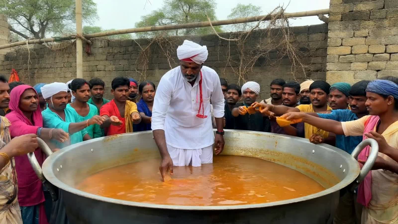 Hindi cook standing waist deep in soup in the middle of a huge pot and serving the street food from the very same pot to...