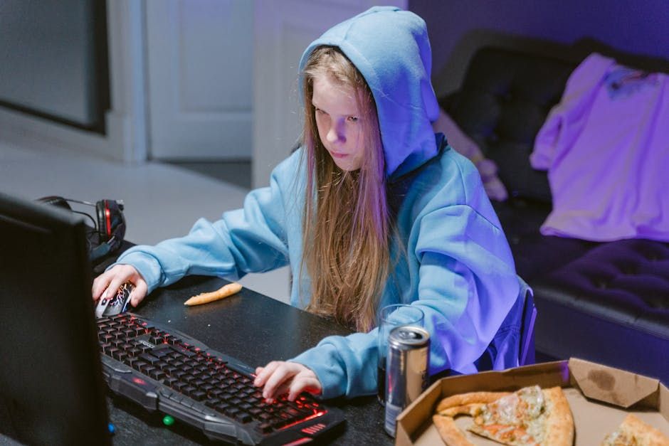 a cute girl using a blue sweater and a blue hoodie. She has long straight blonde hair and is typing in the computer. 