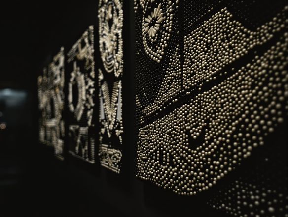 Intricate Native American wampum beadwork patterns, geometric and symbolic, displayed on a rich, dark background with subtle lighting highlighting the texture of the beads.