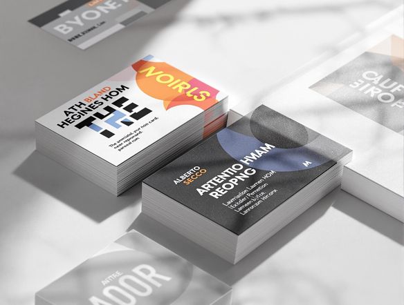 A stack of business cards with various professional designs, fanned out on a clean, modern desk, with soft, directional lighting enhancing the texture and colors.