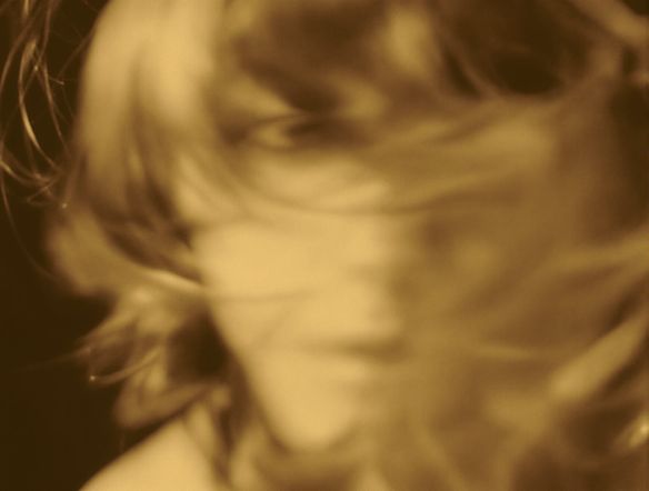 A vintage portrait photograph with eyes gently blinking and hair softly swaying, rendered as a cinemagraph. Subtle motion, soft lighting, sepia tones, animated GIF style.