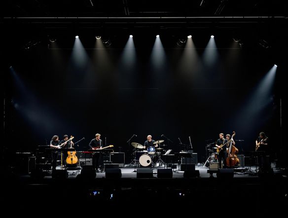 Detailed stage layout diagram for a six-piece band, showcasing instrument placement and member positions, using a clean, minimalist design. Incorporate subtle lighting cues and stage dimensions for clarity. The style should emulate a professional concert venue plan.