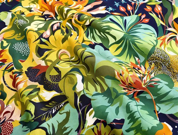 A vibrant, close-up view of a hand-dyed silk fabric showcasing a complex, nature-inspired block print design with rich textures and earthy tones.