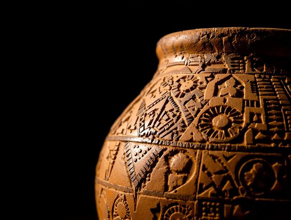 Close-up of a Bug-Dniester culture pottery vessel showcasing detailed incised geometric patterns and abstract motifs, earthy tones, archaeological artifact style.