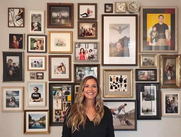 A beautifully arranged photo wall featuring a mix of family portraits, travel snapshots, and abstract art prints. The arrangement should be eclectic and visually appealing, with varying frame sizes and styles. Soft, diffused lighting to enhance the warmth.