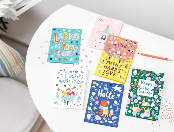 A collection of vibrant and unique greeting cards, each with a distinct theme and design, arranged on a clean, modern surface.