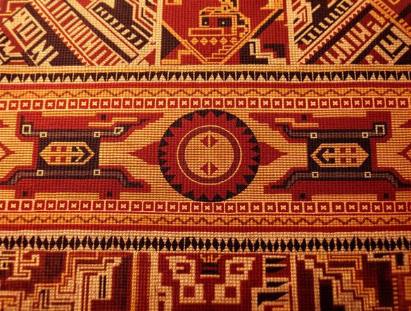 A vibrant, detailed close-up of an Incan textile, showcasing geometric patterns and animal motifs in rich earthy tones. Authentic Andean textile art style, generated by pre-Columbian weaving AI.