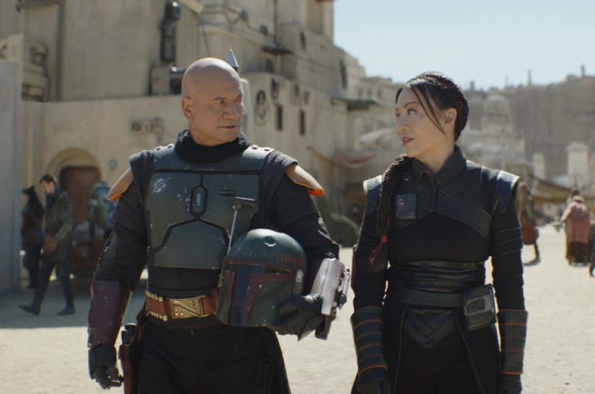 Jon Snow and Daenerys Targaryen, dressed as Mandalorians, wearing black, silver and red armor. Walking through Mos Espa on Tatooine. 
