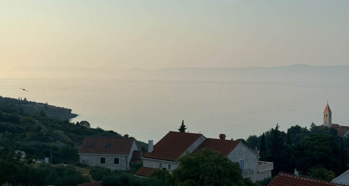 Early morning Adriatic Sea with coastal church tower and red roofed homes in the cypress and olive trees watercolor painting blurry misty mo...