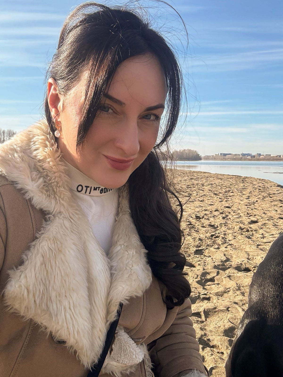 Don't change your face. A girl in a white fur coat is in a photo studio with a Doberman sitting on her shoulders against a plain background.