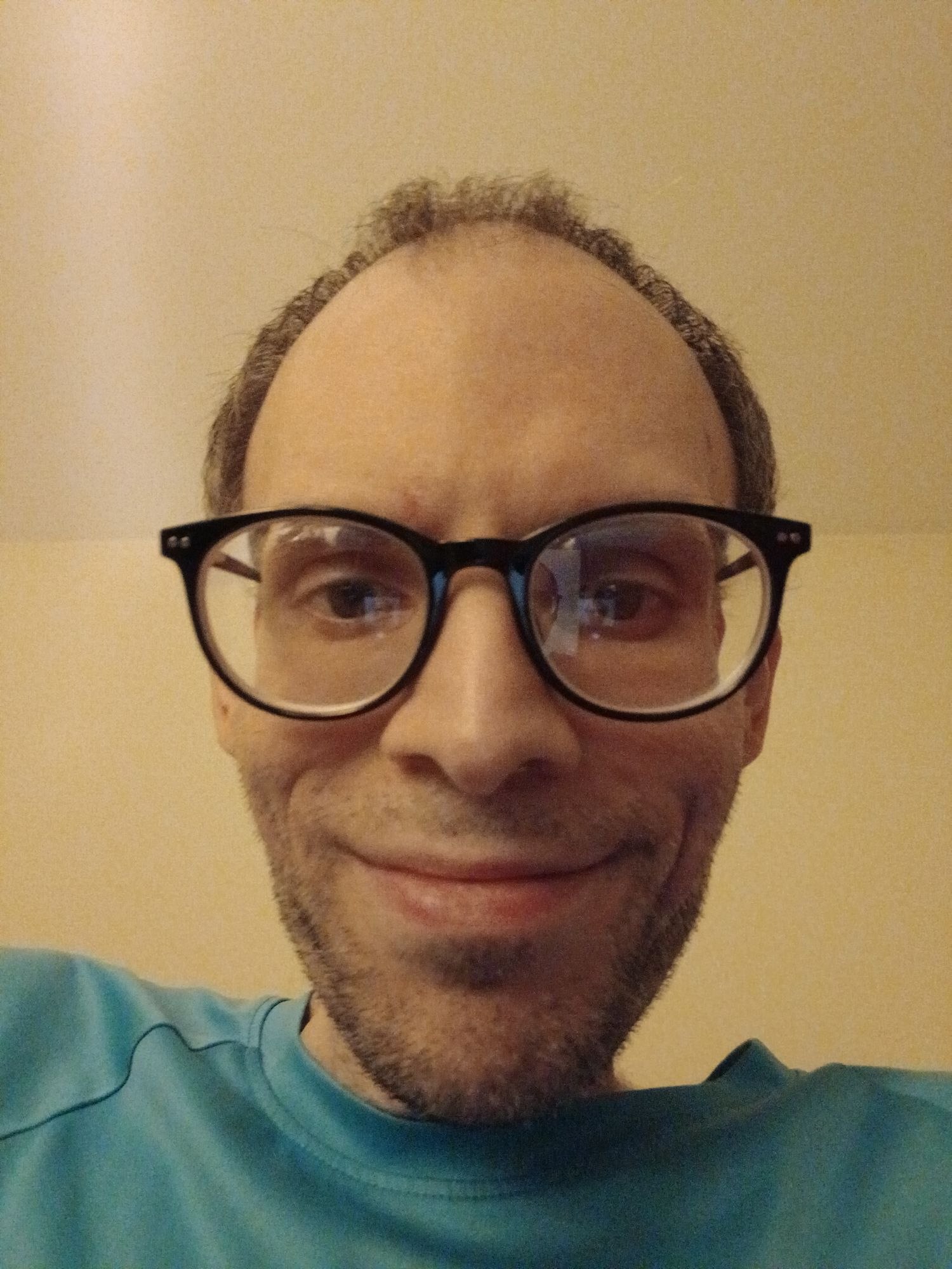 A painter with black glasses smiling 