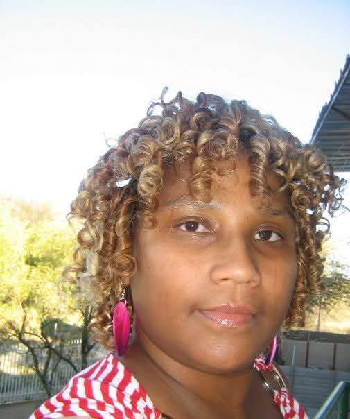 Woman sitting on green grass, holding a rose with her bridal white dress stretching out around her making a beautiful circle of pearls and d...