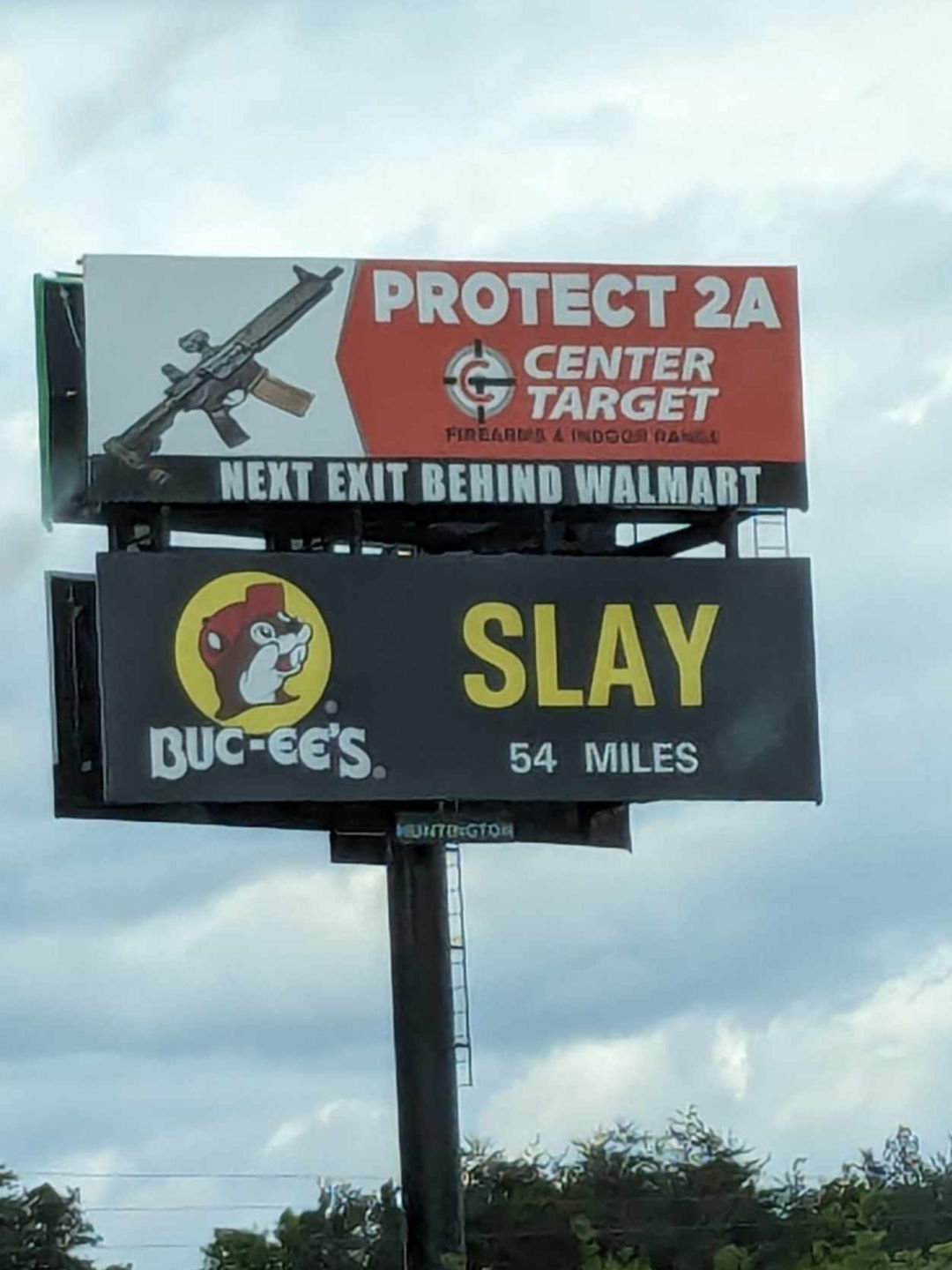 an ironic gun toting billboard in the usa and a second billboard below about gas station