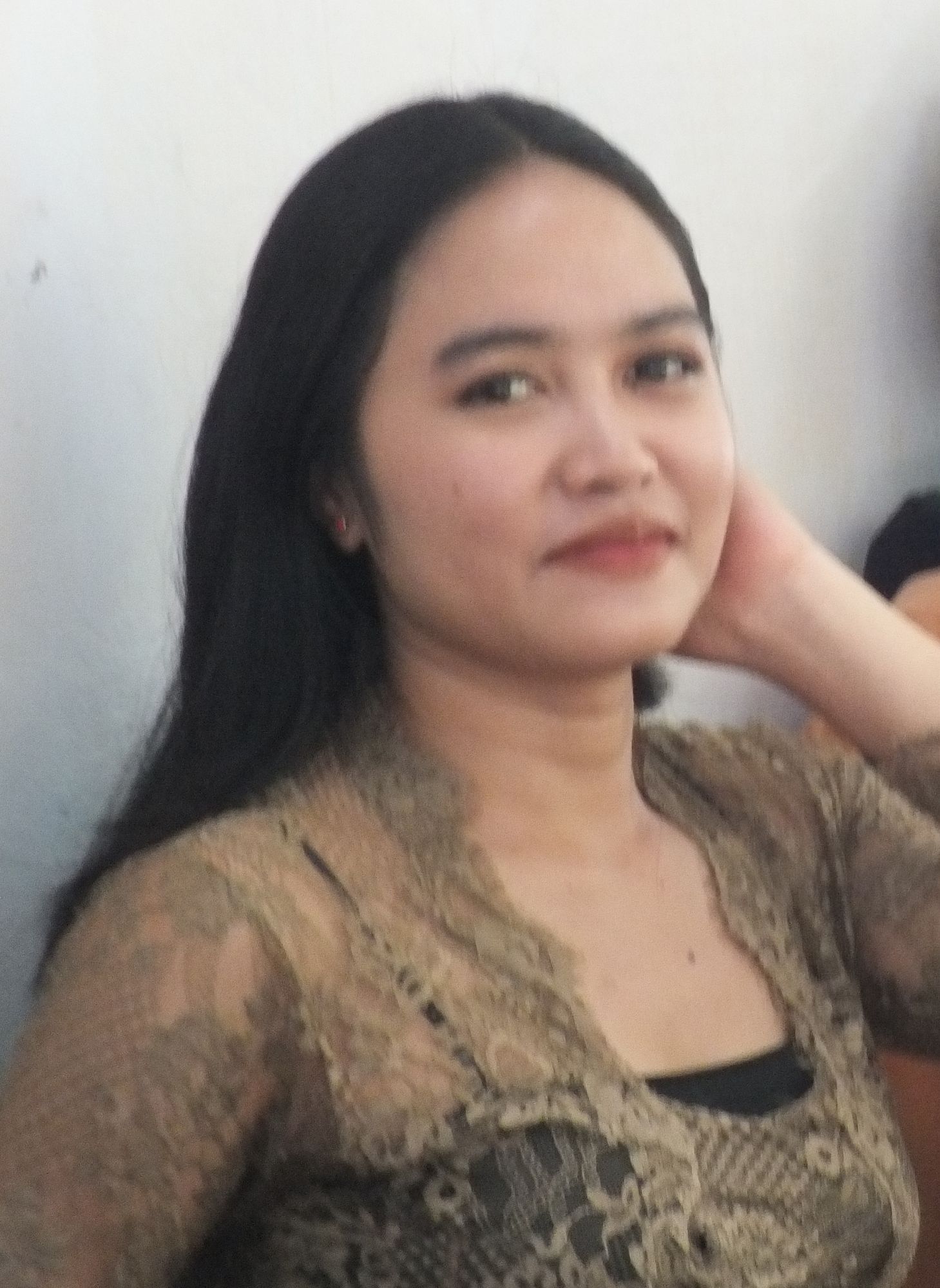 The girl in the picture smiles as she welcomes guests with the traditional Sasak house on Lombok Island in the background, with an old-fashi...