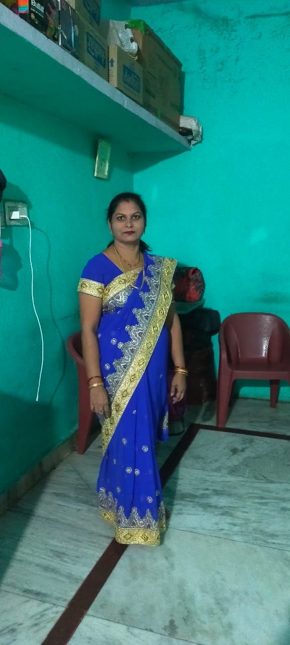 A 4K ultra-realistic portrait of the same woman in the uploaded image, wearing a translucent red saree over a fitted blouse. White flowers b...