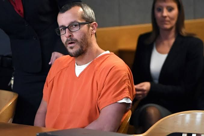 A highly detailed image of a (Chris Watts glaring at camera in an orange prison jumpsuit:1.5) in a courtroom and (cloud of smoke in the back...