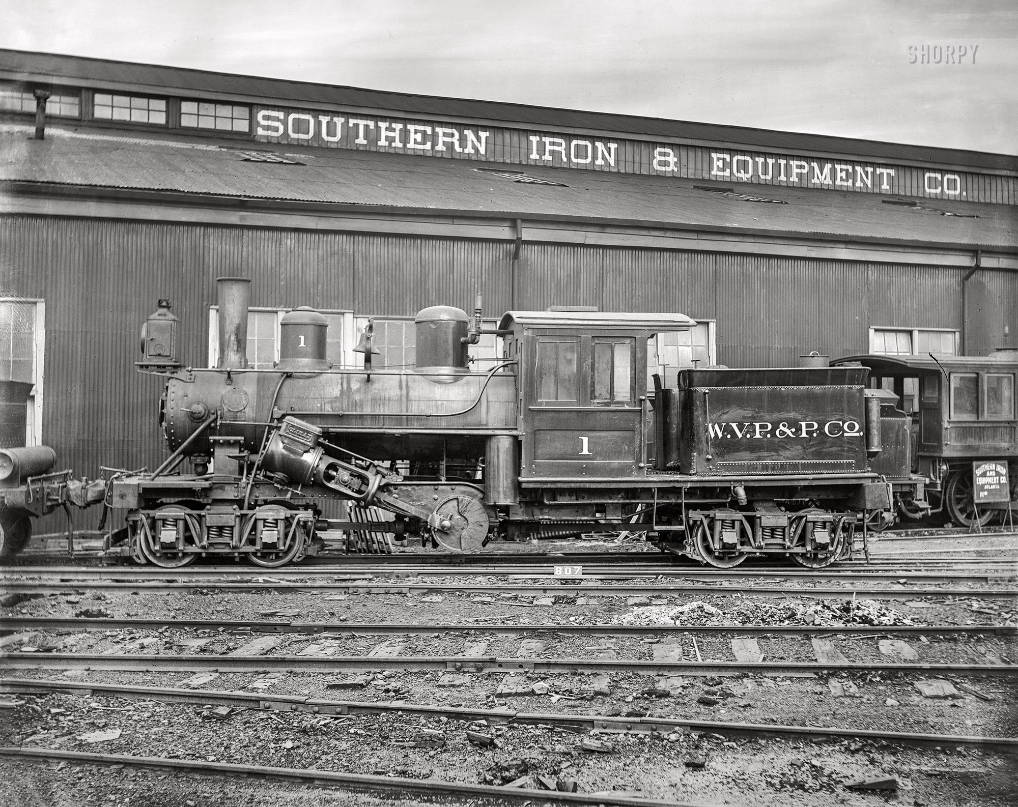 A dusty old locomotive sits in the old rail yard. 