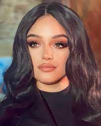 Numidia Lezoul strolling along a metropolitan avenue, long black hair cascading down her back, slender frame wrapped in a sleek black dress,...