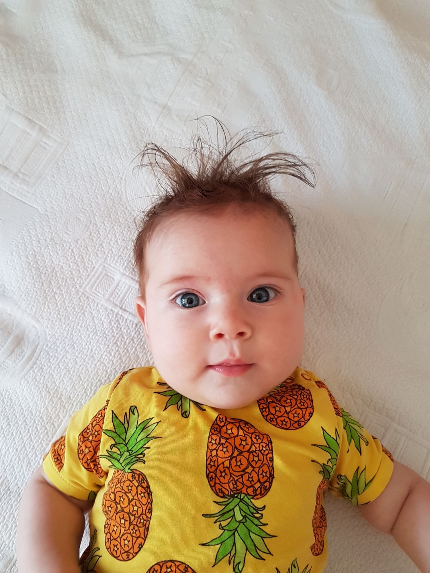 There is a newborn baby girl with blonde hair and blue eyes.