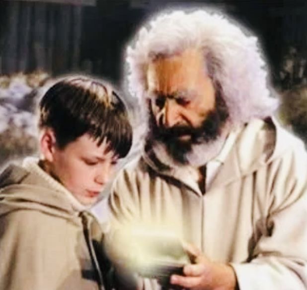 A young boy with brown hair and An old man with white hair looking at a small glowing magic box.