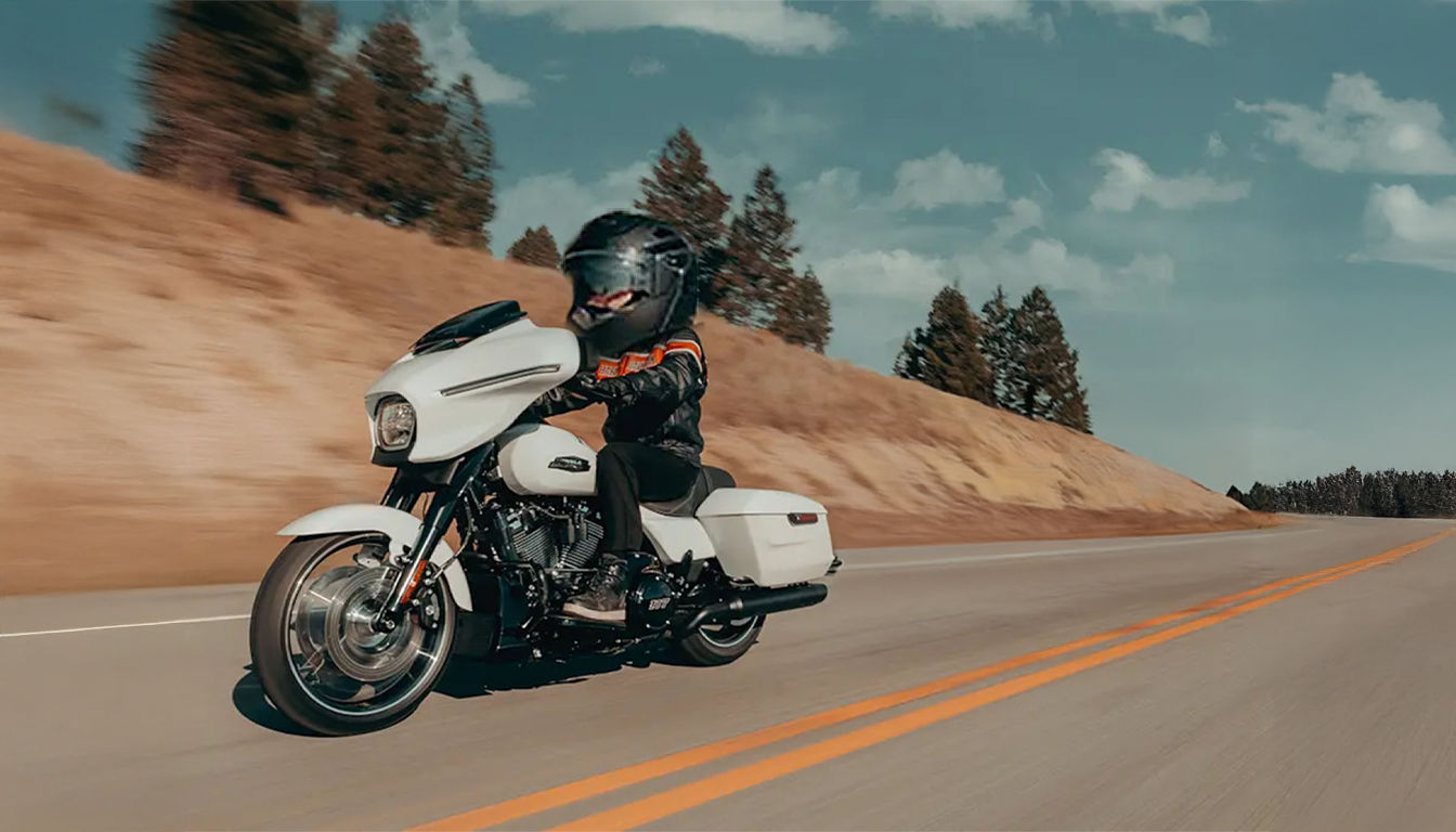 A miniature toy biker on a Harley Davidson Street Glide riding on a sunny highway.
