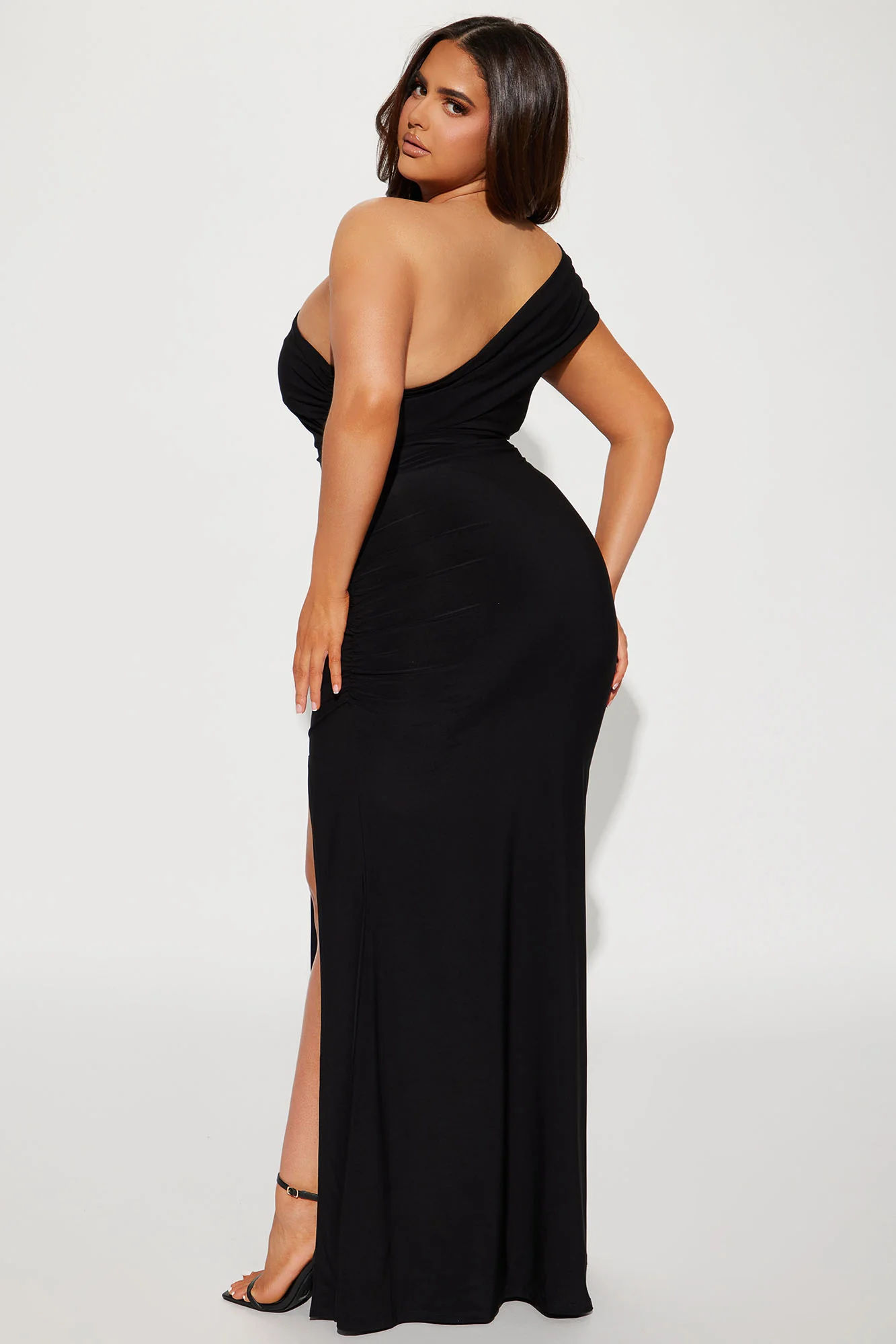 Female 1960s black and white filter noir spy beautiful diamond necklace black dress rich agent black heels at the casino leaning against a p...