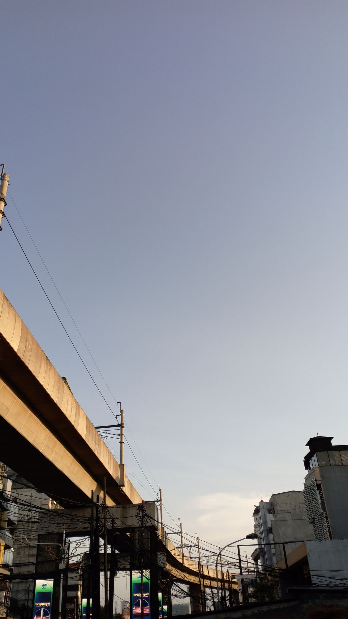 An urban scene featuring a high overpass bridge and surrounding buildings in the soft light of the late afternoon. The golden hour sunlight...