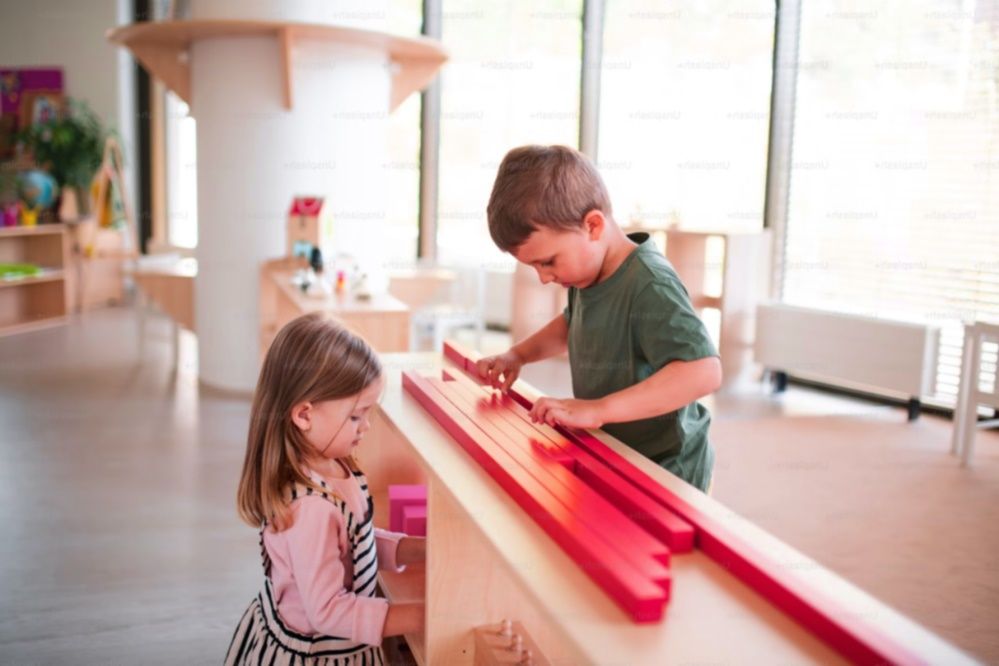 A little girl and a little boy playing with toys in kindergarten school.