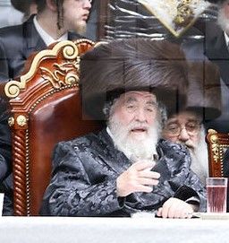 A painting of the Rebbe of Viznitz, Rabbi Yisrael Hager, sitting at the head of a large table. The Rebbe of Viznitz is the one in the center...