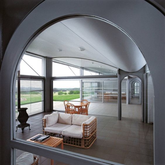 Interior of a living room design by Glenn Murcutt with warm lights and a view to the outside through the window blinds and contemporary wood...