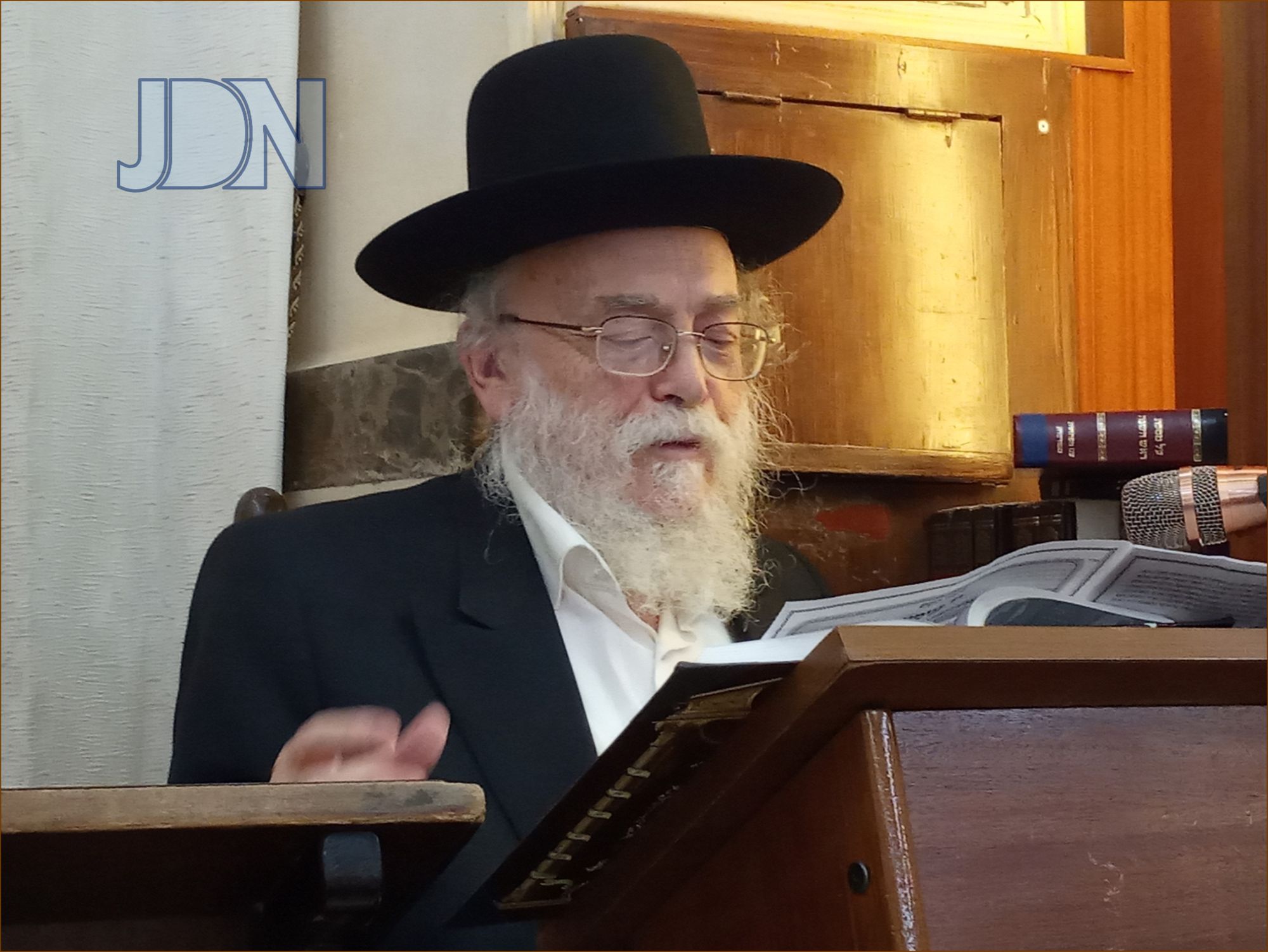 Old man in his sixties, smart, reading a book, short white hair, long beard, smiling, library background