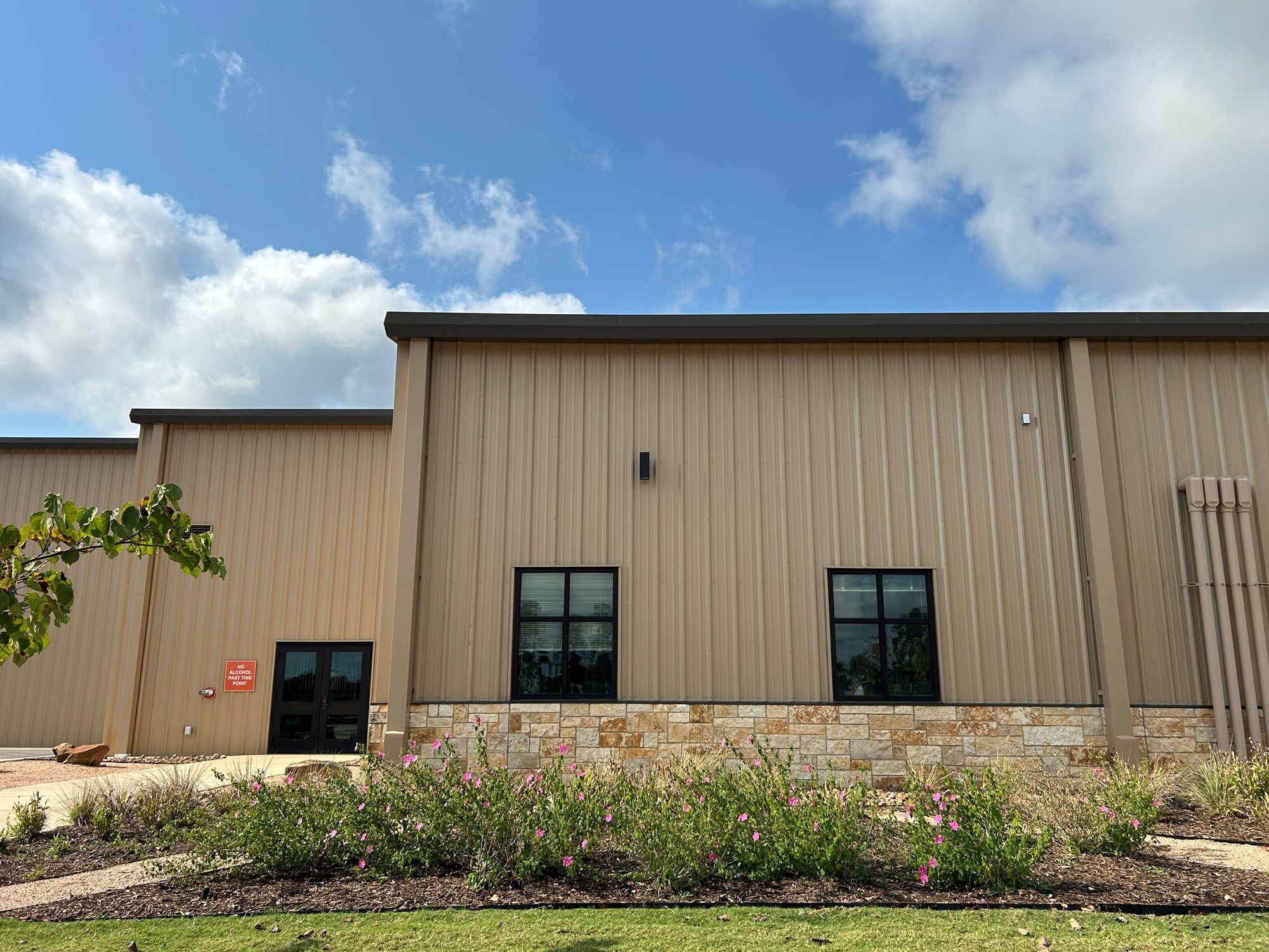 Maintain the existing building exactly as it is. Remove all the planting landscape. Replace with desert style landscape to include large roc...