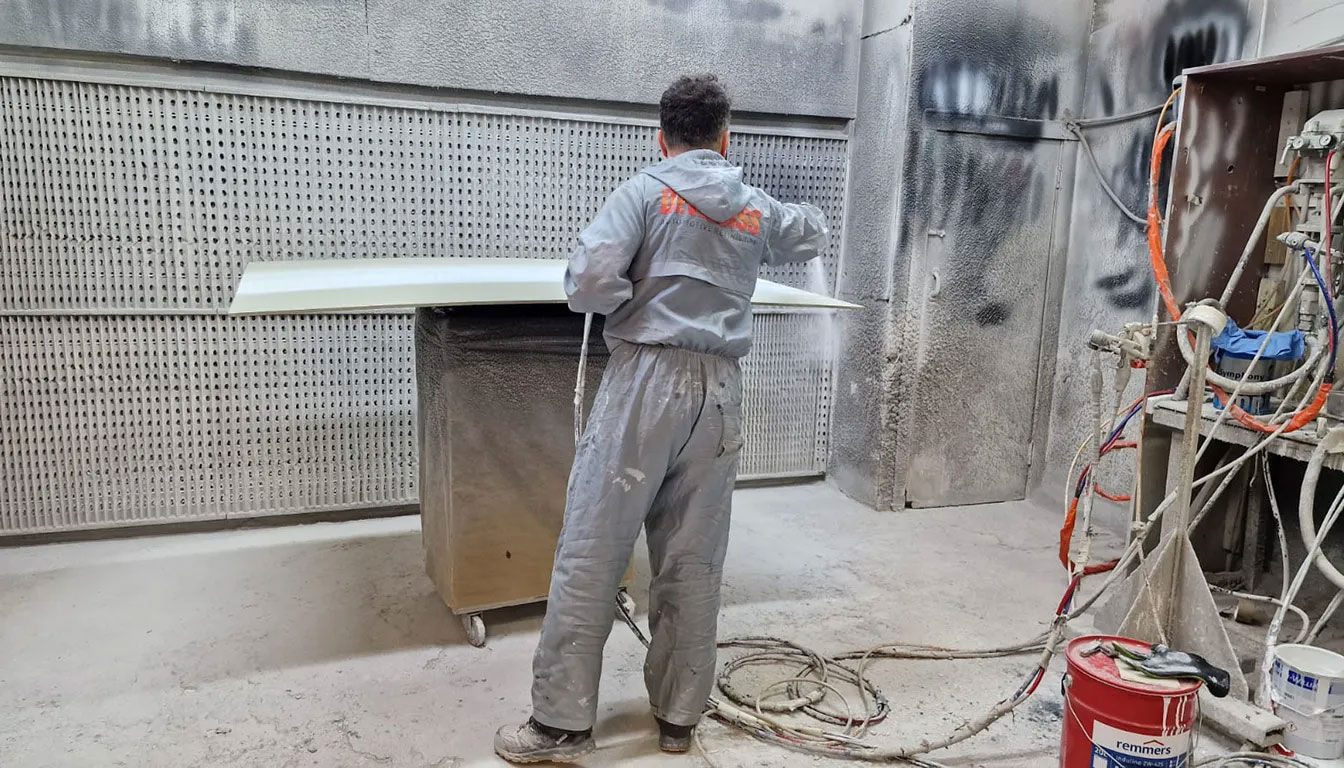 a spray paiter working in spray room. he is painting wood furniture