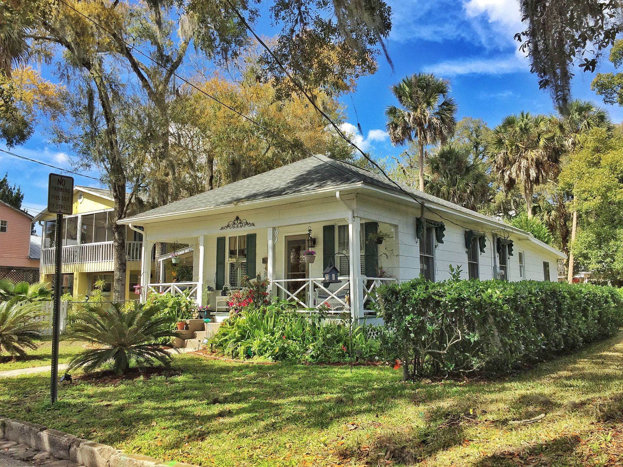 Charming white cottage surrounded by flower gardens and palm trees
