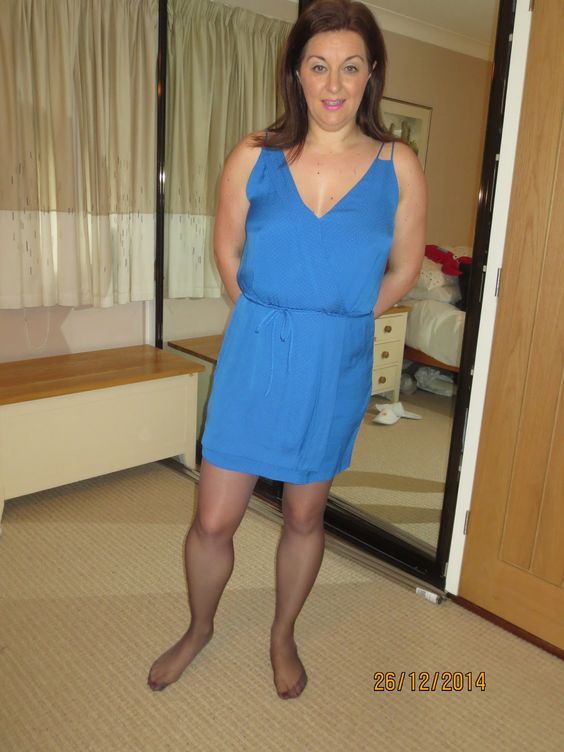 "Another Day"  full body all in frame Dark Haired Woman late 30's size 14 40 D in deep cut deep sky blue mid thigh wrap dress black pantyhose legs fit the...