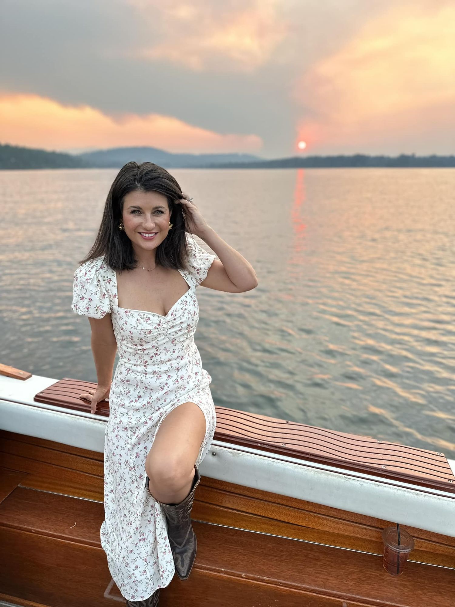 "What is more beautiful?  Me or The Sunset? Well, the sun is behind a cloud now and there is a thunderstorm brewing" 

Dark Haired Women sitting with her left leg showing through slit in her sundress samiling at you sitting on side of mid sized motorboat on c...