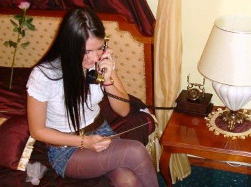 She says "what?" and laughs with a blushing smile shifting and moving her right leg up slightly